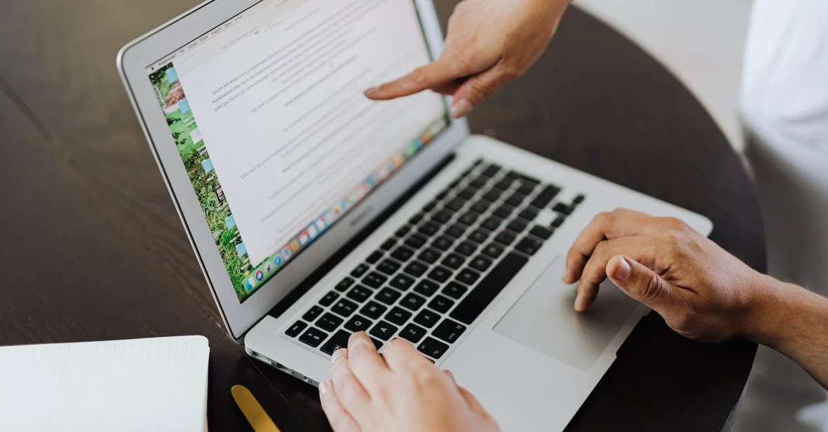 Deux personnes collaborant sur un projet avec un ordinateur portable dans un environnement de bureau.