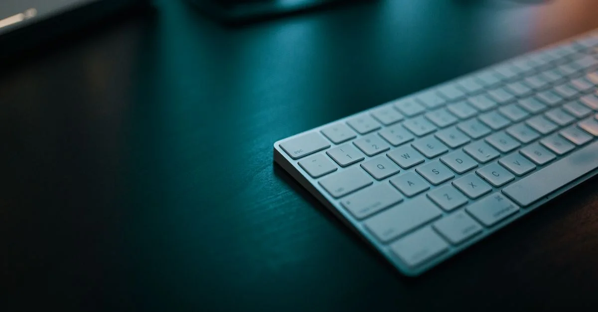 Clavier blanc élégant sur un bureau sombre, idéal pour les thèmes de bureau moderne.