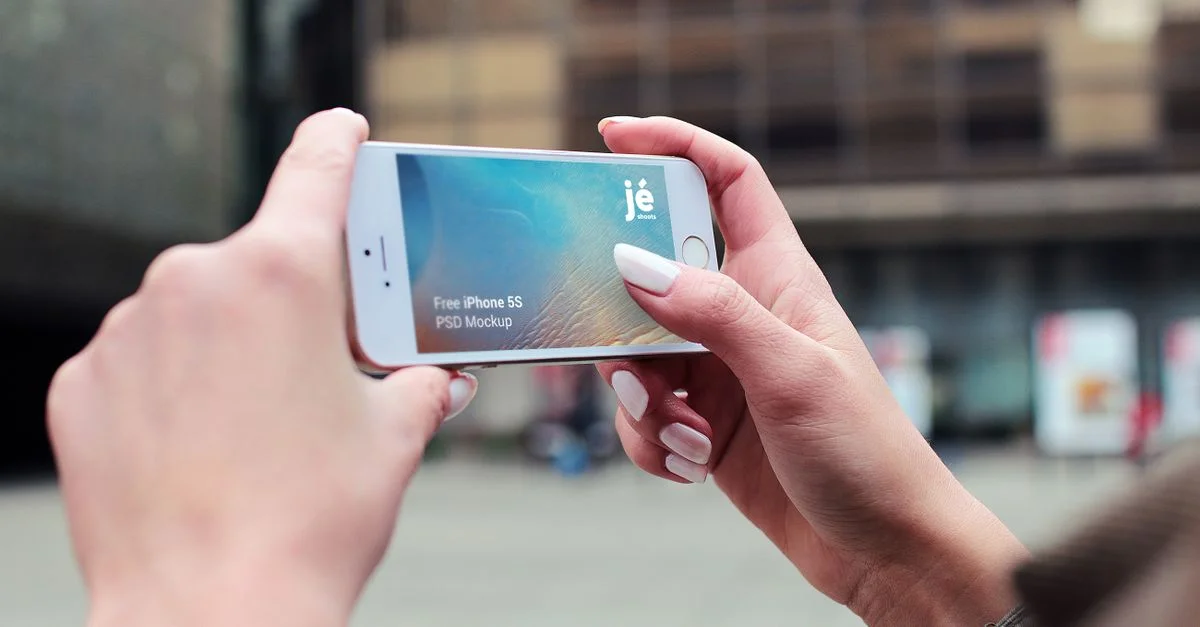 Gros plan de mains tenant un smartphone élégant contre un paysage urbain moderne.