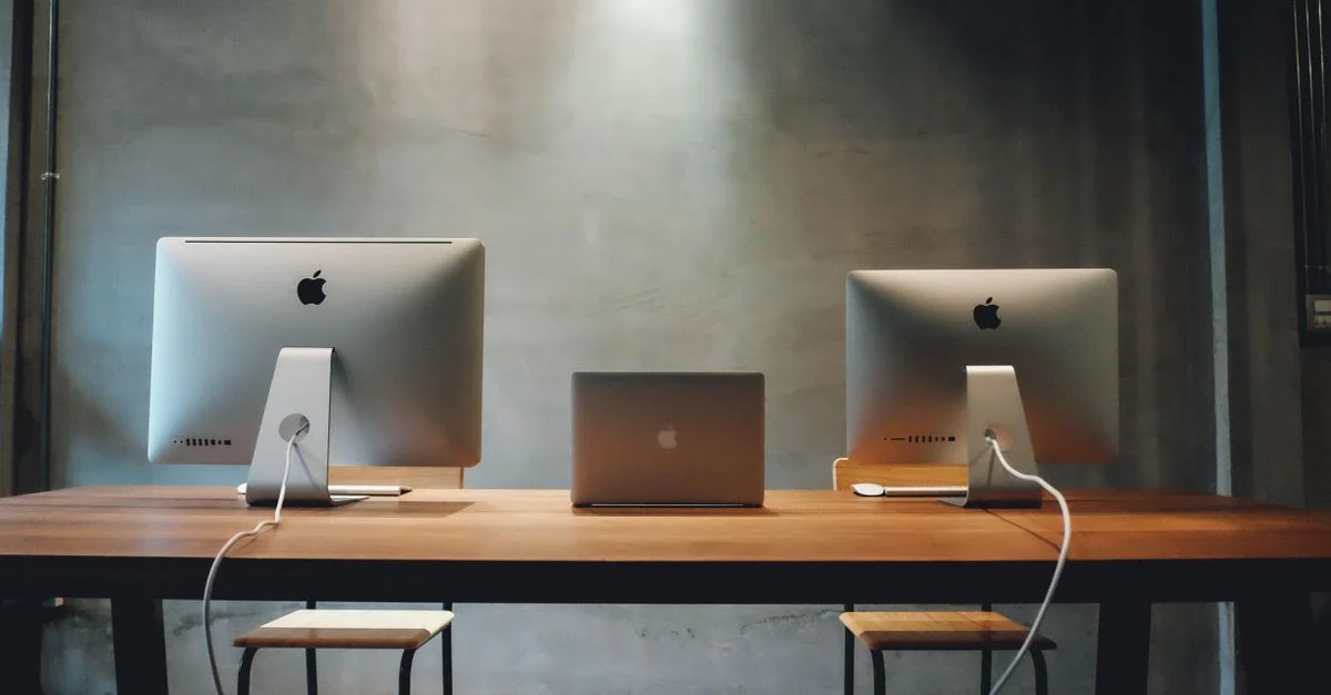 Espace de bureau minimaliste avec des écrans doubles sur une table en bois, favorisant un environnement de travail contemporain.