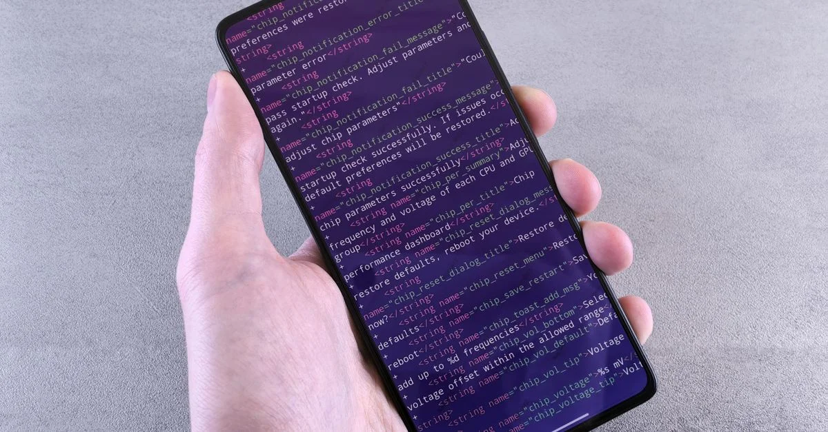 Gros plan d'un smartphone affichant un texte de code tenu dans la main d'une personne.